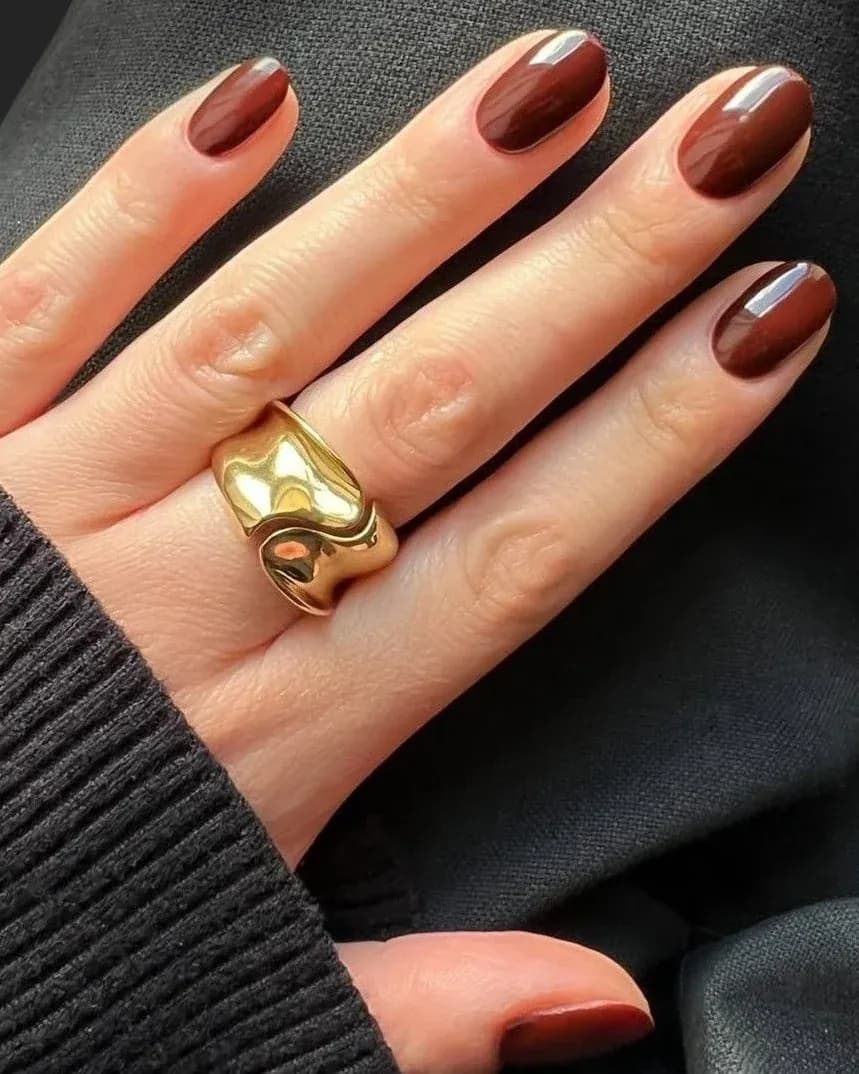 Uñas marrón chocolate con anillo dorado
